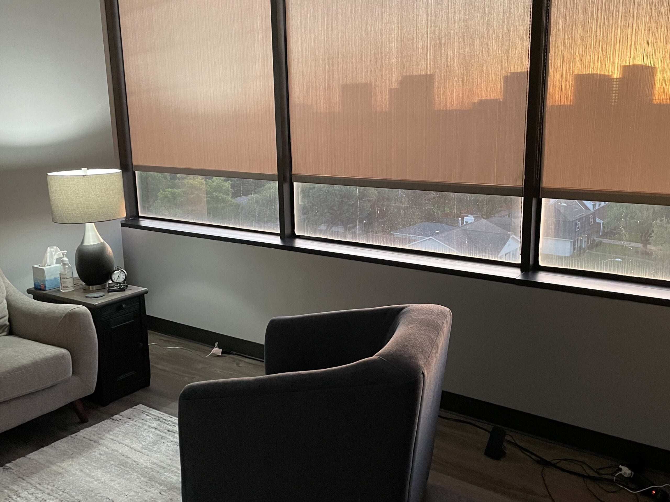 A room with a chair and a window overlooking a city