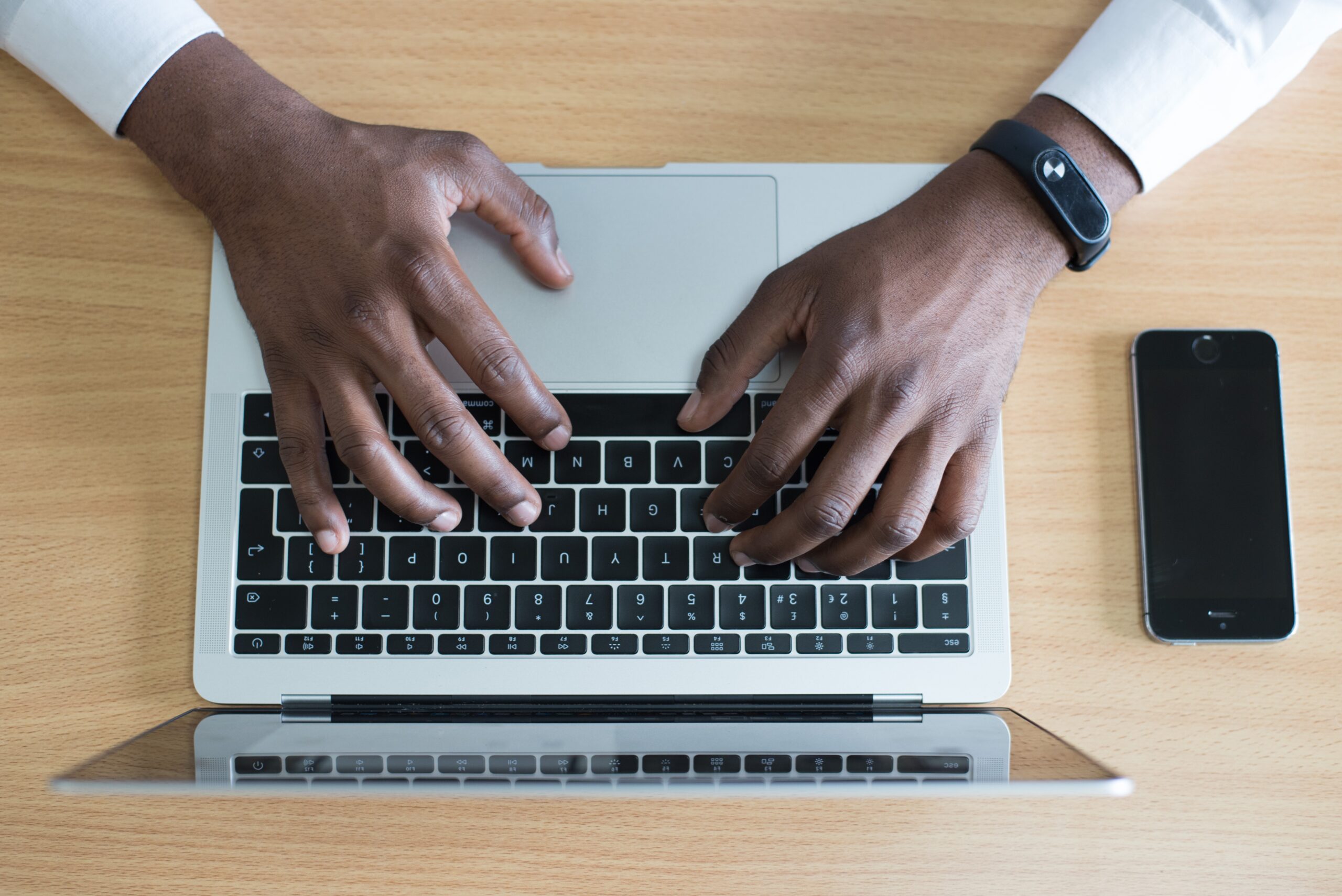 A man's hands typing on a laptop